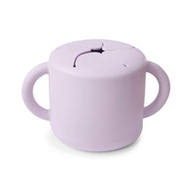 Mushie Silicone Snack Cup in Soft Lilac, featuring a lid with a slit for easy snacking and two handles for grip.