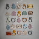 Mushie Silicone Ball Teether in Woodchuck color, surrounded by various silicone teething toys in playful shapes and colors.