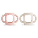 Silicone bottle handles in blush and shifting sand colors, designed for easy gripping by children.