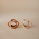 Silicone bottle handles in natural and shifting sand colors, designed for easy gripping by children.