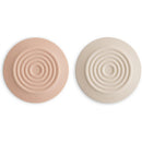 Silicone drain stoppers in blush and shifting sand colors, featuring concentric ring designs.