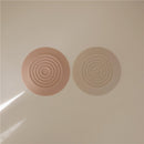 Silicone drain stoppers in blush and shifting sand colors, featuring concentric circle designs.