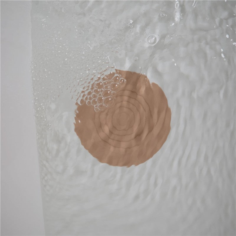 Mushie silicone drain stopper in blush color floats on water surface, designed to prevent drainage while enhancing decor.