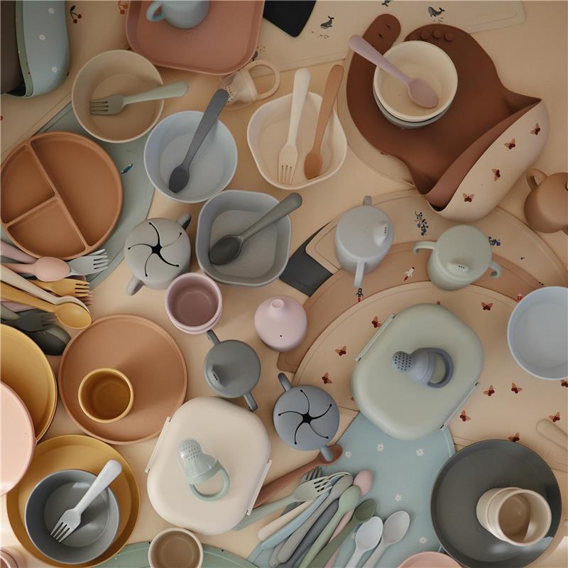 Mushie silicone placemat featuring a non-slip design with playful planets, surrounded by colorful dishware and utensils.