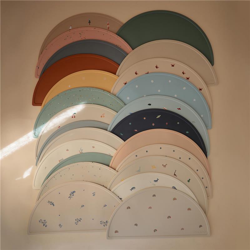 Mushie silicone placemats for kids in various colors and designs, showcasing planets and playful patterns.