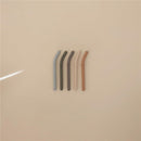 Silicone straws in forest colors: light blue, dark green, beige, light brown, and dark brown, arranged on a beige background.