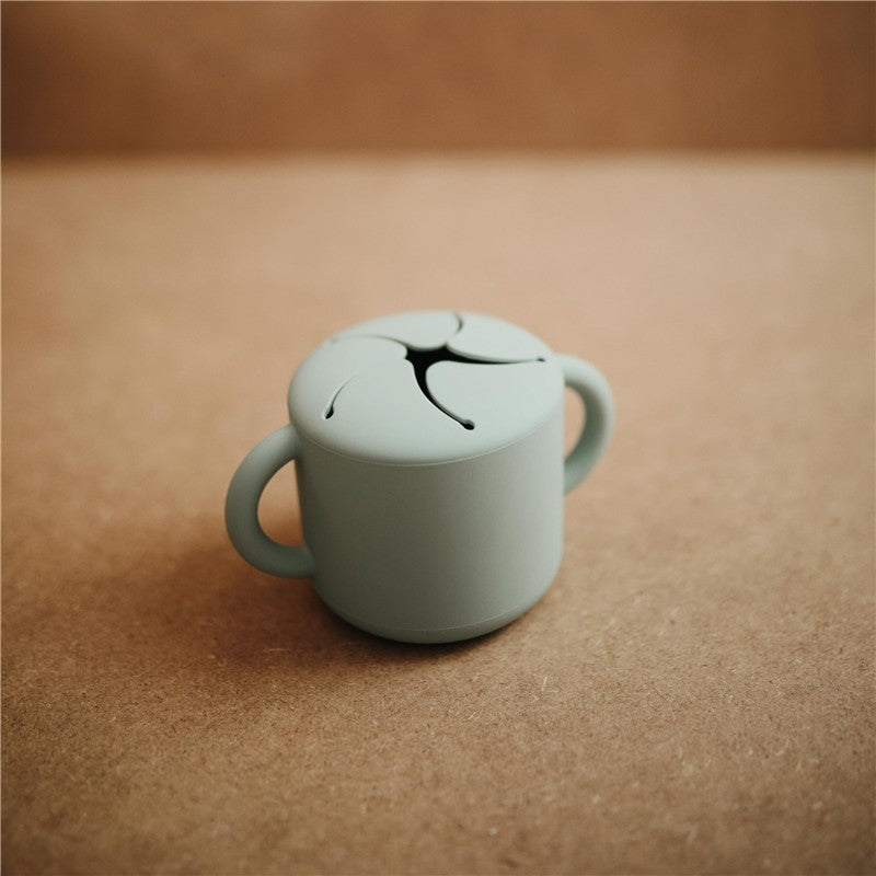 Mushie Silicone Snack Cup in Cambridge Blue, featuring a smooth finish and two handles, ideal for toddlers.