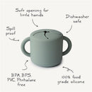Mushie Silicone Snack Cup in green with soft opening, spill-proof design, and features listed as dishwasher safe and BPA-free.