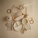 Mushie silicone suction plate in ivory with various matching feeding accessories arranged on a neutral background.