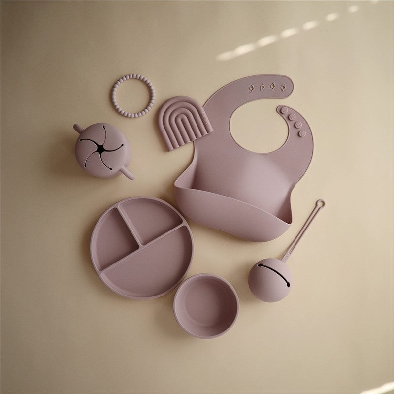 Soft lilac silicone suction plate set with various accessories including a bib, divided plate, bowl, and utensils.