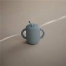 Mushie Silicone Training Cup in powder blue with two handles and a straw, designed for young children.