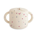 Mushie Snack Cup in cream with colorful star patterns, featuring two handles and a slot for easy snacking.