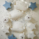 Mushie Snack Cup in white with star designs, surrounded by star-shaped confetti and a blue star-shaped object.