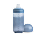 Mushie Soft Spout Sippy Cup in Tradewinds color, with a transparent body and a blue lid, next to a matching dome-shaped cap.