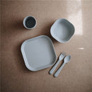 Mushie Silicone Square Plate Dinnerware Set in Cloud, featuring a square plate, bowl, cup, fork, and spoon.