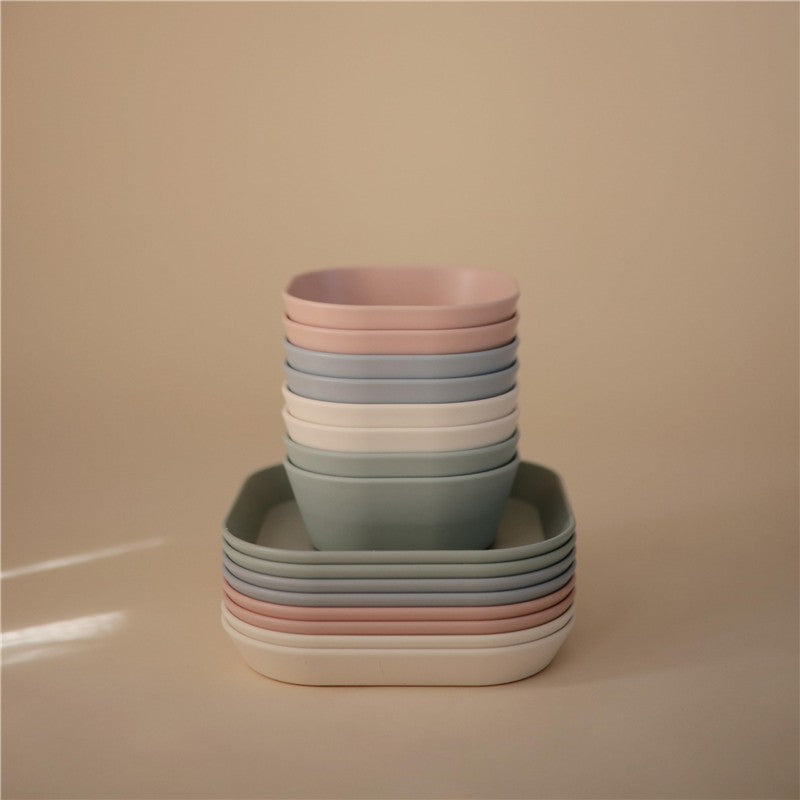 Mushie Silicone Square Plate Dinnerware Set in soft pastel colors stacked, featuring a square plate and round bowls.
