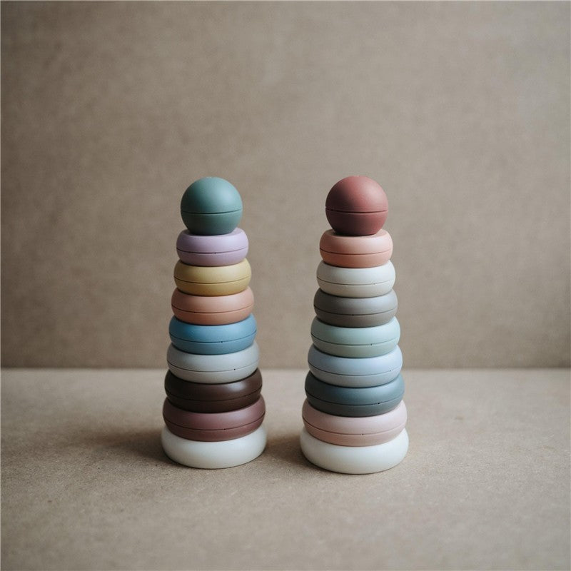 Mushie Stacking Rings in rustic colors, featuring two towers of variously sized pastel rings.