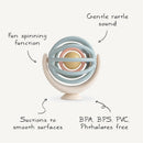 Mushie Suction Spinner Ball in pastel colors, featuring a spinning function, gentle rattle sound, and suction base, BPA free.