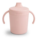 Mushie Trainer Sippy Cup in blush color, featuring ergonomic handles and a soft silicone spout.