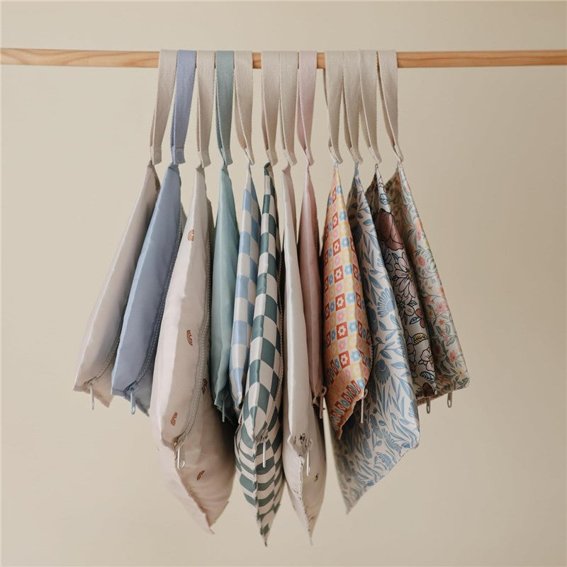 Water-resistant wet bags in various colors and patterns, neatly hanging with straps, designed for practical storage.