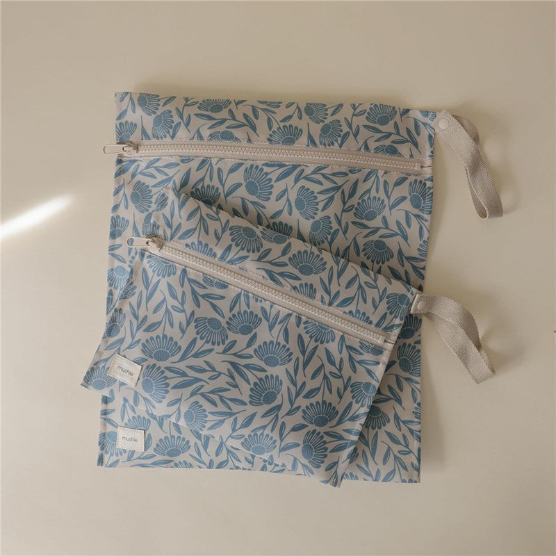 Mushie water-resistant wet bags in a blue floral design, featuring two sizes with zip closures and fabric loops.