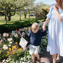 Mother and child walking in a flower garden, child holding a Mushie water-resistant wet bag in a floral design.