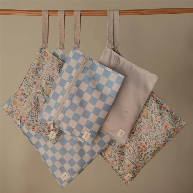 Water-resistant wet bags featuring floral and checkered designs, displayed hanging with zippers visible.