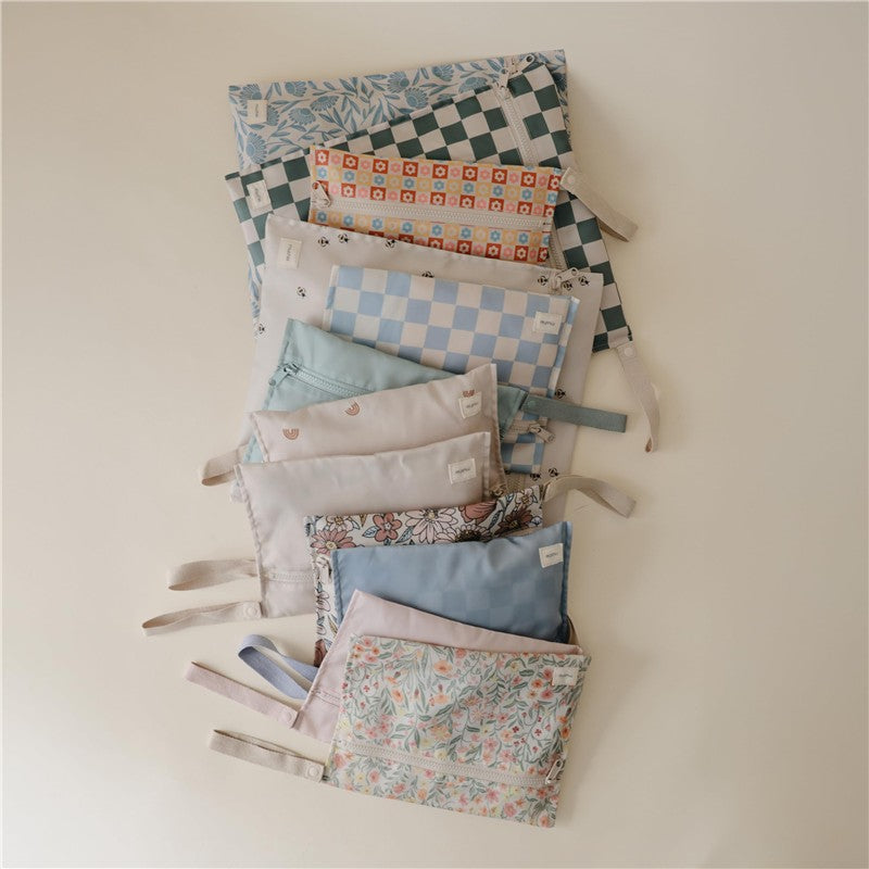 Mushie Water-Resistant Wet Bag set featuring various colorful patterns and textures, arranged neatly on a light background.