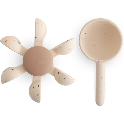 Mushie Water Wheel Bath Toy features a star-shaped wheel with colorful speckles and a scoop for pouring water.