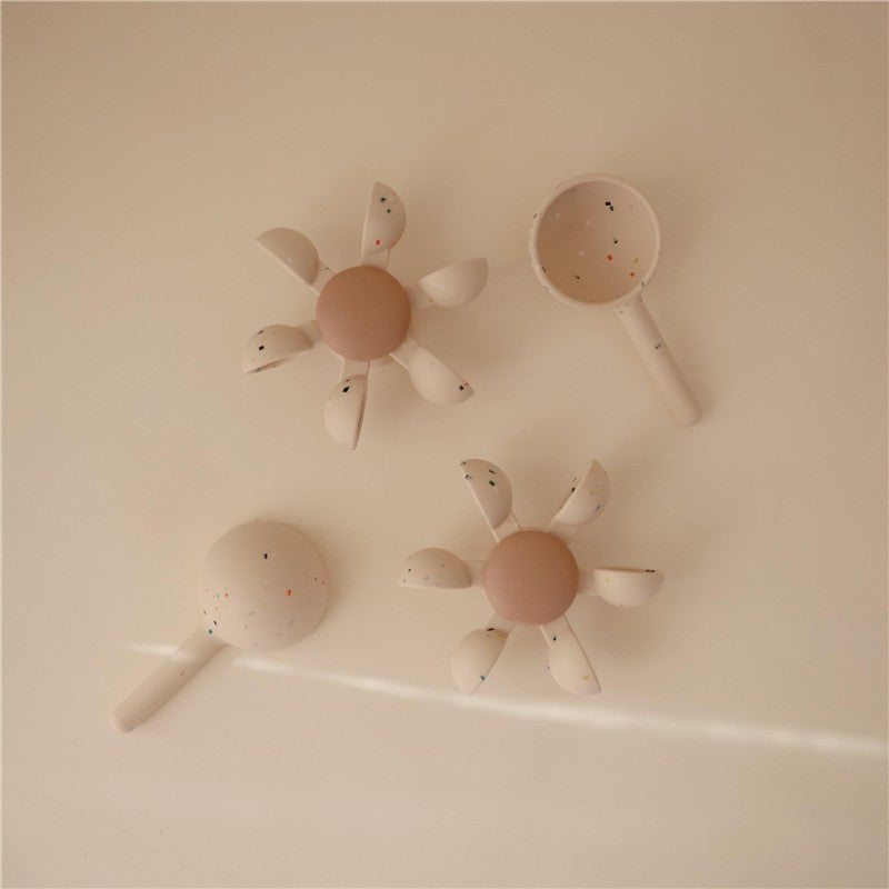 Mushie Water Wheel Bath Toy set featuring two flower-shaped wheels and a scoop, designed for fun water play.