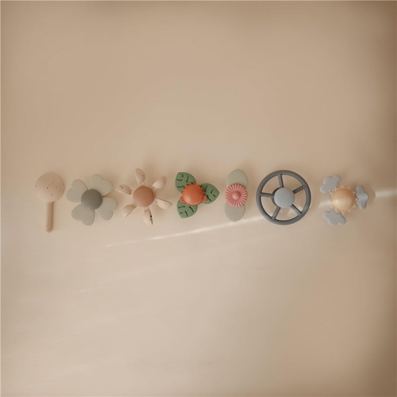 Colorful Mushie Water Wheel Bath Toy set featuring various playful designs including flowers and a steering wheel.