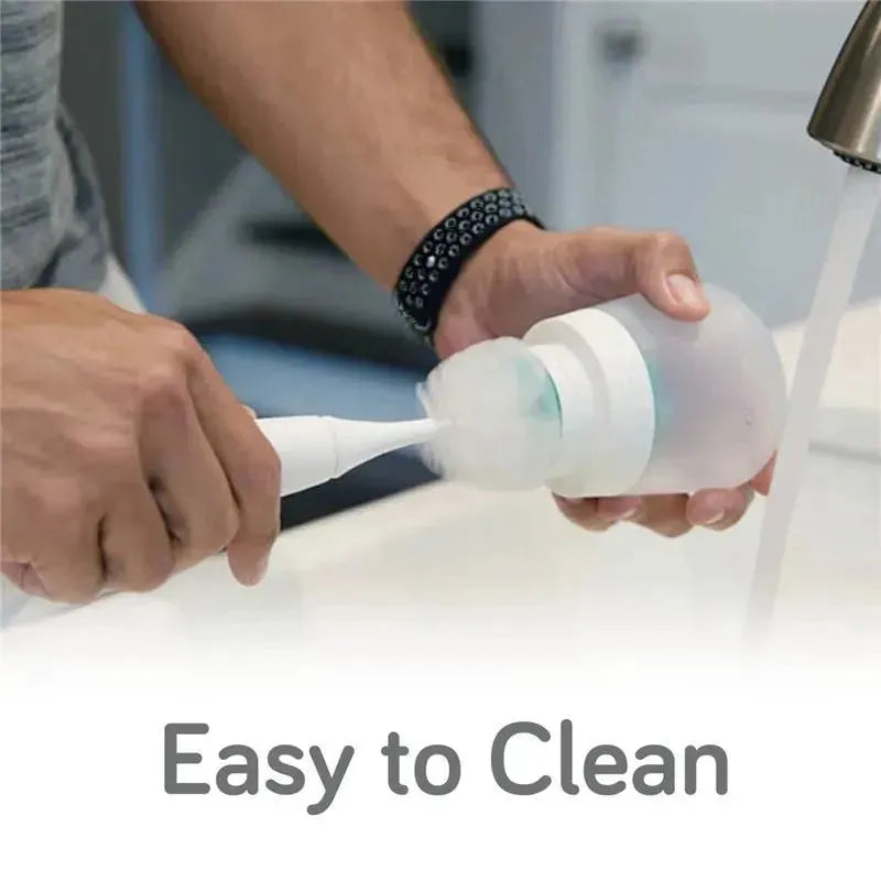 A person cleaning a Nanobebe Flexy Silicone Baby Bottle with a brush under running water.