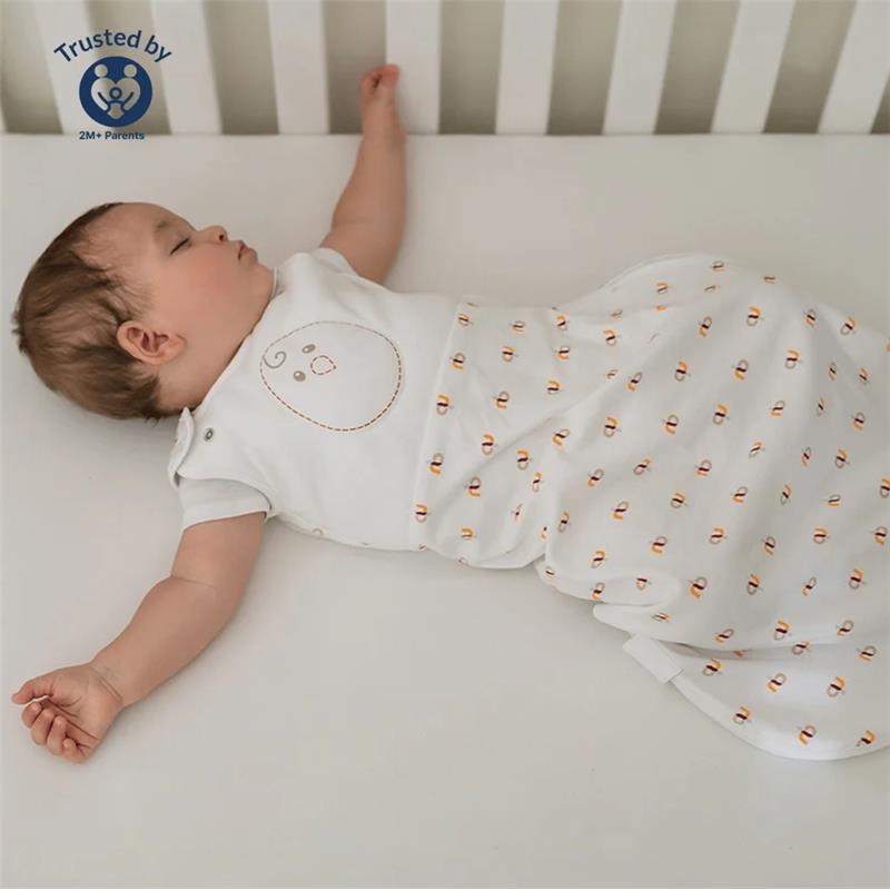 Soft pink Nested Bean Zen Sack Classic for infants, featuring a smiling face design, worn by a sleeping baby in a crib.