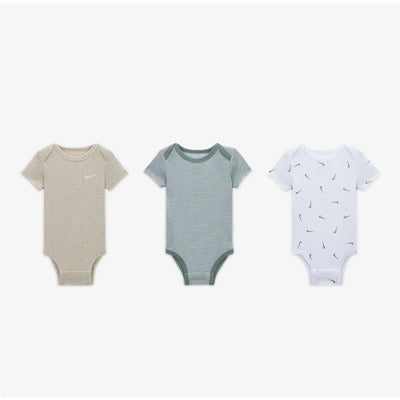 Three unisex newborn bodysuits by Nike: beige with logo, green striped, and white with small logos.