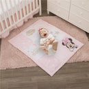 Baby lying on a pink Minnie Mouse-themed play mat featuring cloud, star, and crescent moon designs, smiling joyfully.