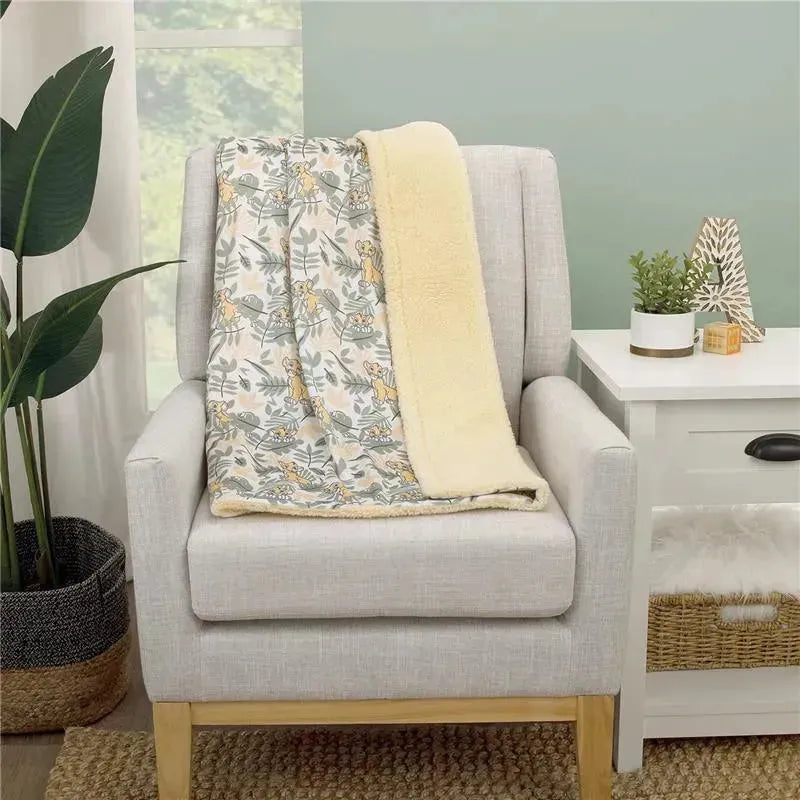 Super soft baby blanket featuring Disney’s Lion King Simba design with a Sherpa backing, displayed on a chair.