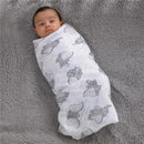 Muslin swaddle with Dumbo prints, wrapping a baby, on a soft gray blanket.