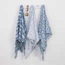 Three printed muslin swaddles featuring Mickey Mouse designs in blue tones hanging on a white pegboard.