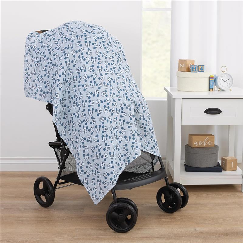Mickey Mouse printed muslin swaddle draped over a stroller, showcasing a blue design with cartoon mickey faces.