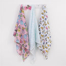 Three muslin swaddles from Nojo: pink with princesses, light blue with a pattern, and white with multi-colored princess designs.