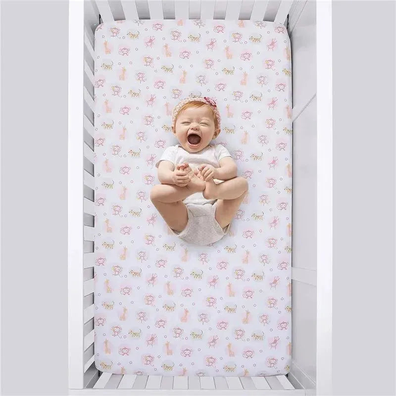 Fitted crib sheet featuring a playful animal pattern, with a smiling baby lying on it in a white crib.