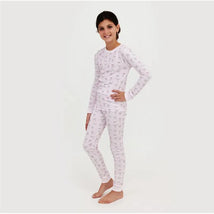 Long sleeve pajama set for girls featuring a light pink pattern of bows, model posing with a smile.