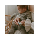 Baby grooming kit in Lily Blue being used by a caregiver to brush the hair of a seated baby.