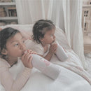 Two young girls seated on a bed, each holding a light purple Nouka insulated stainless steel water bottle featuring a ballerina design.