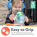 Child wearing blue headphones smiling while holding a Nuby Clik-It 360 Flip-It Cup with two handles and a straw.
