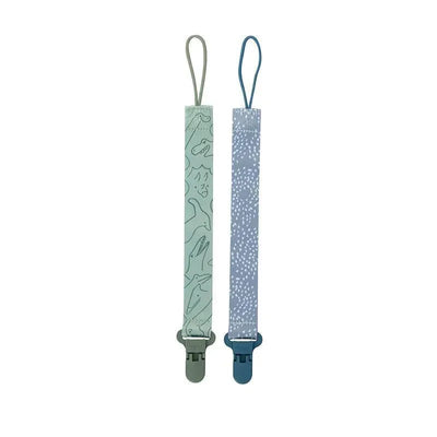Two fabric pacifier clip holders for boys featuring blue polka dots and green dinosaur patterns, with plastic clips.