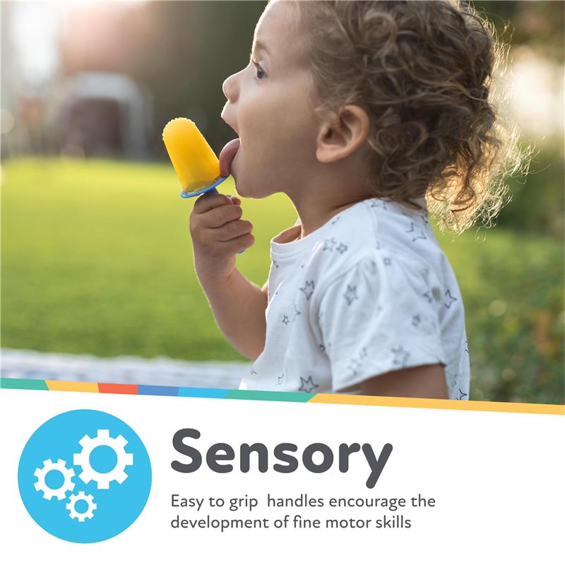 A young child with curly hair joyfully licks a yellow popsicle while holding it in a blue silicone mold, set in a grassy outdoor area.