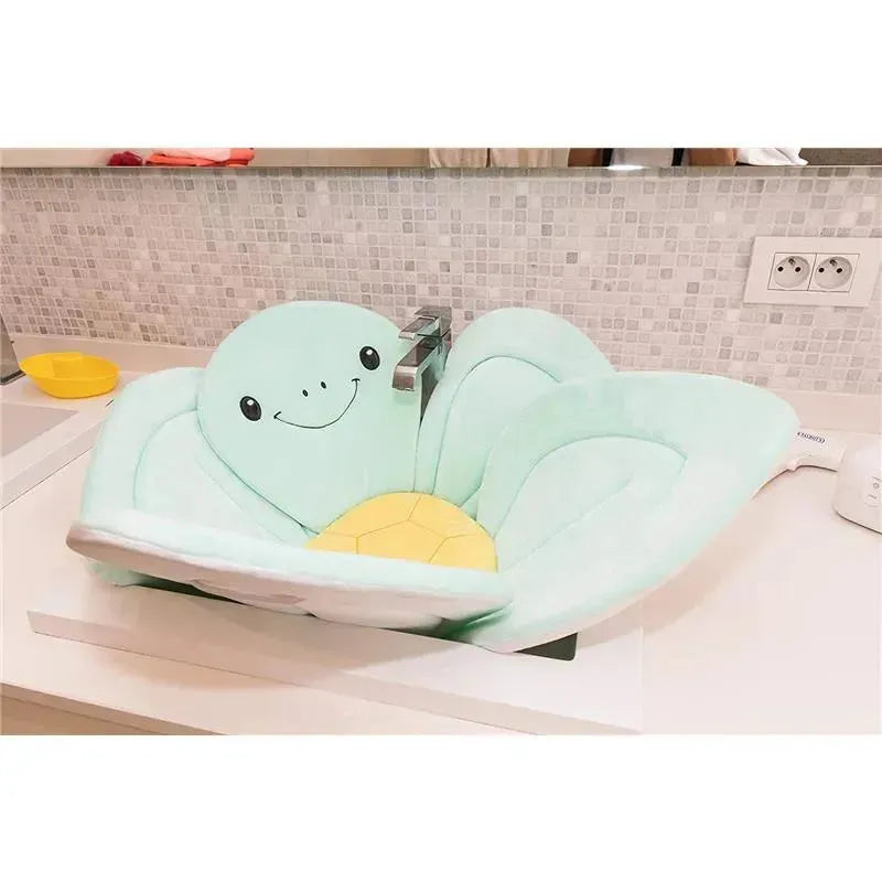 Nuby Bathing Turtle baby bath sink insert in soft mint green with a smiling turtle face and yellow shell, designed for infant bathing.