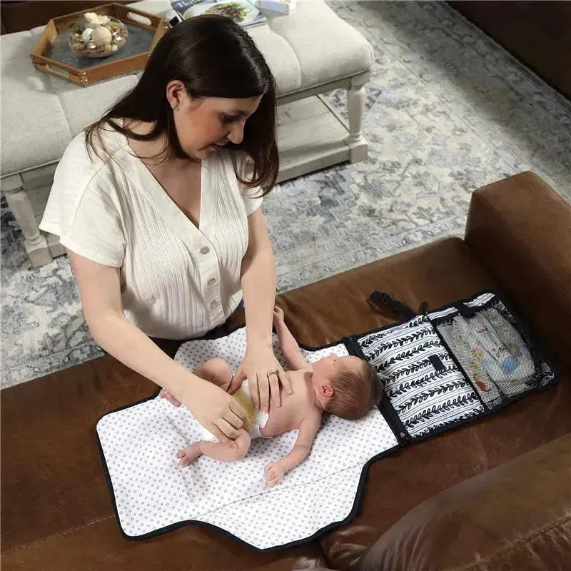 Portable changing pad laid out on a sofa, with a mother changing her baby’s diaper. The pad includes a zippered storage case.