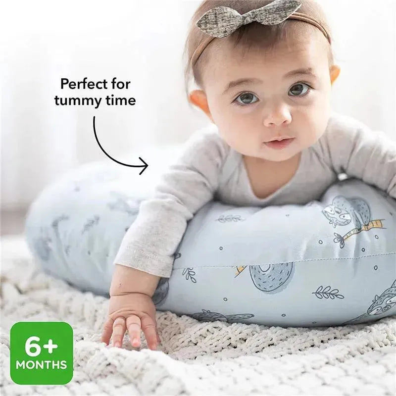 Infant rests on a blue nursing pillow with zoo animal prints, promoting tummy time; suitable for ages 6 months and older.